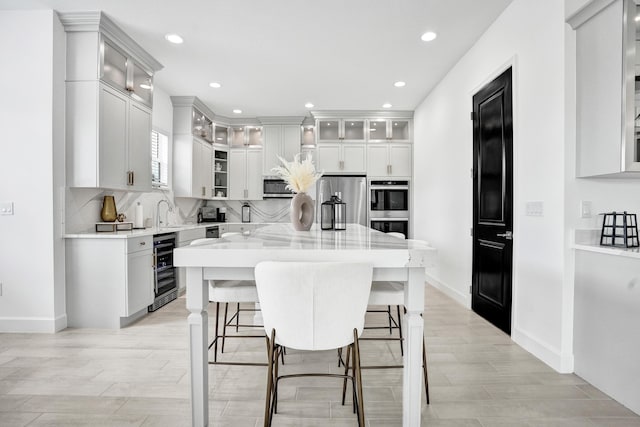 5609 Zestar Ln, The Acreage, FL 33470 - kitchen featuring appliances with stainless steel finishes, beverage cooler, tasteful backsplash, a center island, and baseboards
