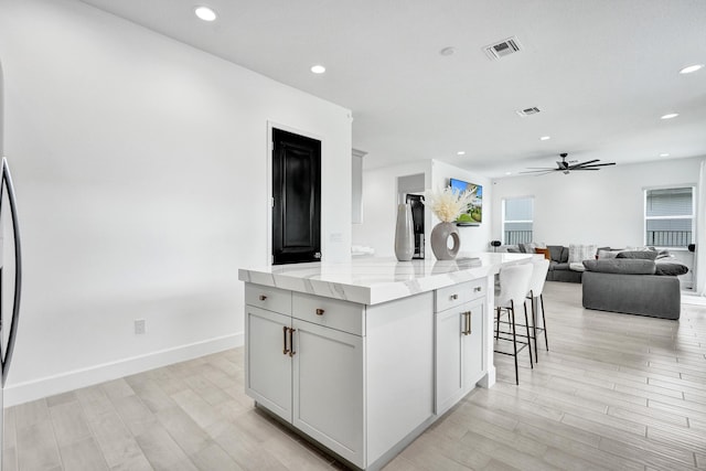 5609 Zestar Ln, The Acreage, FL 33470 - kitchen with a kitchen island, light wood-style floors, a kitchen breakfast bar, ceiling fan, and open floor plan