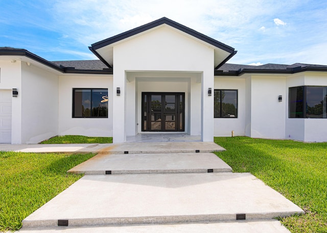 640 Marshall Rd, West Palm Beach, FL 33413 - view of exterior entry featuring stucco siding, a lawn, roof with shingles, and an attached garage