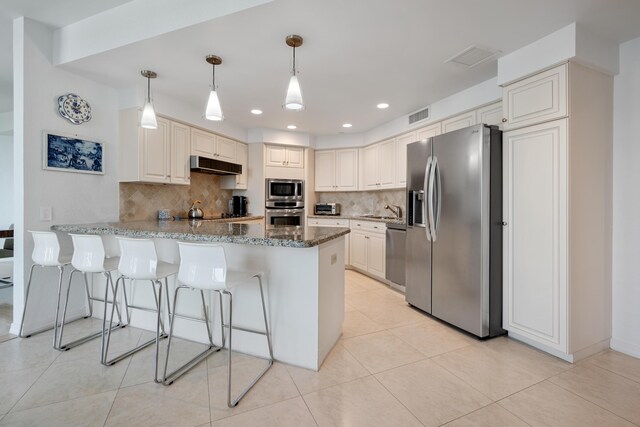 20310 Fairway Oaks Dr Unit 161, Boca Raton, FL 33434 - kitchen with stainless steel appliances, under cabinet range hood, a peninsula, tasteful backsplash, and dark stone countertops