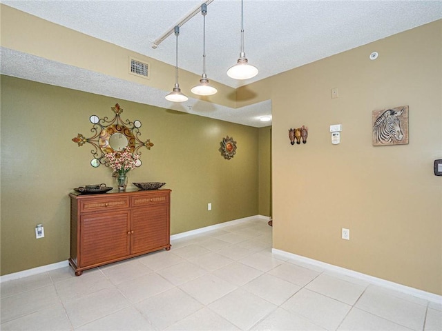 1590 S 42nd Cir Unit 106, Vero Beach, FL 32967 - empty room featuring light tile patterned floors, a textured ceiling, rail lighting, and baseboards