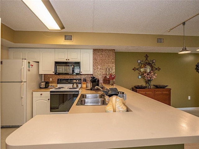 1590 S 42nd Cir Unit 106, Vero Beach, FL 32967 - kitchen with white appliances, a sink, white cabinets, a peninsula, and light countertops