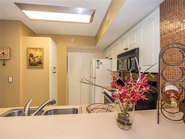 1590 S 42nd Cir Unit 106, Vero Beach, FL 32967 - kitchen with black microwave, a sink, white cabinets, range, and light countertops