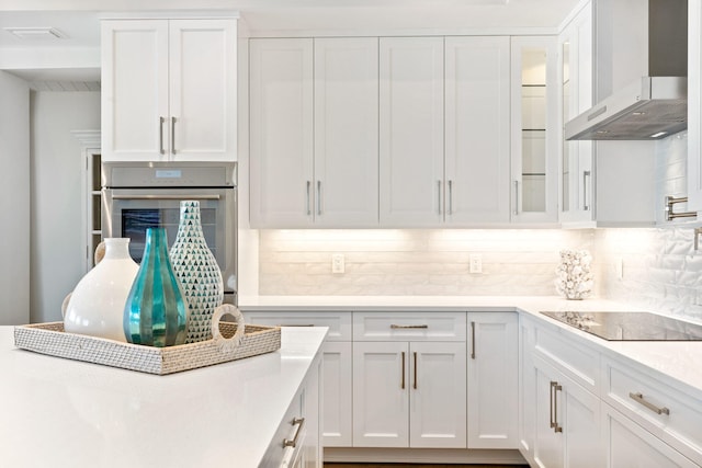 18119 SE Federal Hwy, Tequesta, FL 33469 - kitchen featuring wall chimney range hood, oven, black electric cooktop, and white cabinetry