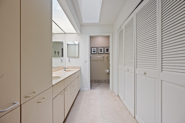 5200 SE Seascape Way Unit 201, Stuart, FL 34997 - bathroom featuring a closet, double vanity, baseboards, and a skylight