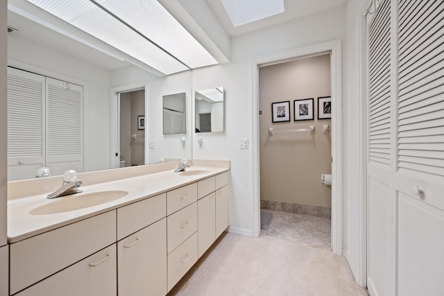 5200 SE Seascape Way Unit 201, Stuart, FL 34997 - bathroom featuring a closet, double vanity, a skylight, and baseboards