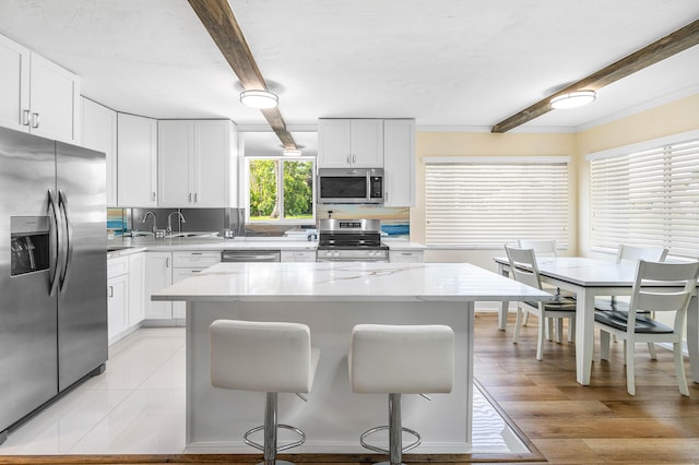 2020 Lake Osborne Dr Unit 10, Lake Worth, FL 33461 - kitchen with appliances with stainless steel finishes, beam ceiling, a kitchen bar, white cabinets, and crown molding