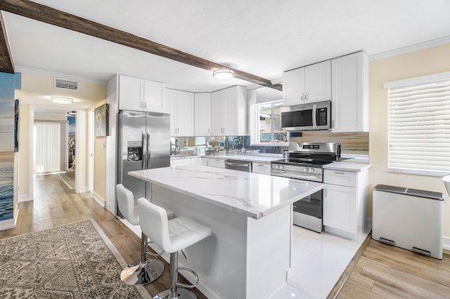2020 Lake Osborne Dr Unit 10, Lake Worth, FL 33461 - kitchen with appliances with stainless steel finishes, crown molding, white cabinetry, a breakfast bar, and a center island