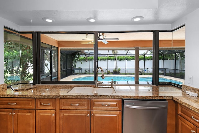 515 SE Nome Dr, Port Saint Lucie, FL 34984 - kitchen with stainless steel dishwasher, a sink, a ceiling fan, and brown cabinetry