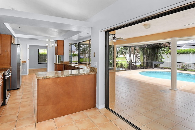 515 SE Nome Dr, Port Saint Lucie, FL 34984 - kitchen with stainless steel appliances, brown cabinets, and light tile patterned floors