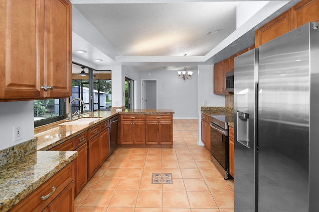 515 SE Nome Dr, Port Saint Lucie, FL 34984 - kitchen with appliances with stainless steel finishes, a sink, brown cabinetry, a peninsula, and light tile patterned floors