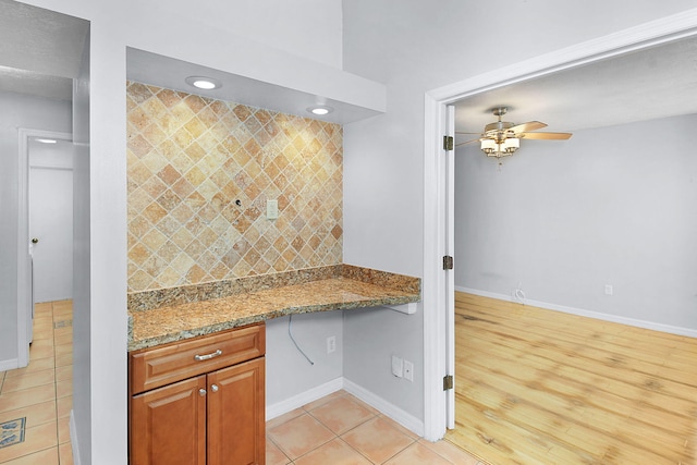 515 SE Nome Dr, Port Saint Lucie, FL 34984 - kitchen featuring ceiling fan, baseboards, light stone counters, brown cabinets, and light tile patterned flooring