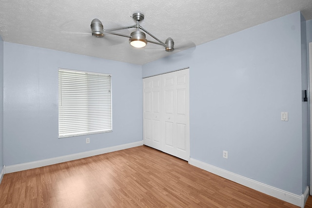 515 SE Nome Dr, Port Saint Lucie, FL 34984 - unfurnished bedroom with baseboards, a closet, light wood-style floors, a textured ceiling, and a ceiling fan