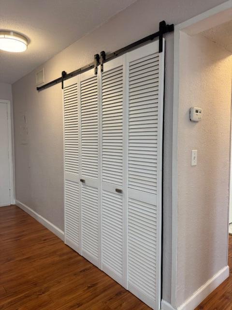 6080 Forest Hill Blvd Unit 201, West Palm Beach, FL 33415 - hall with a barn door, wood finished floors, and baseboards