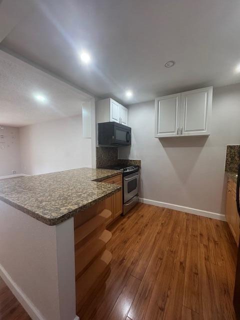 6080 Forest Hill Blvd Unit 201, West Palm Beach, FL 33415 - kitchen featuring black microwave, stainless steel range, a peninsula, wood finished floors, and baseboards