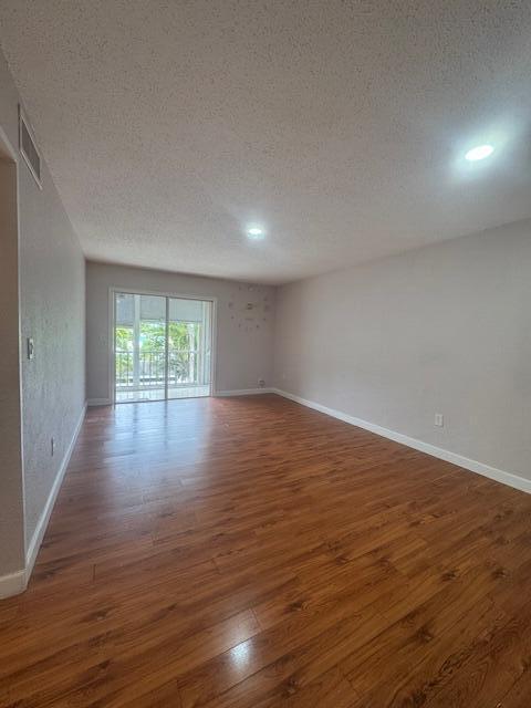 6080 Forest Hill Blvd Unit 201, West Palm Beach, FL 33415 - unfurnished room featuring a textured ceiling, wood finished floors, baseboards, and recessed lighting