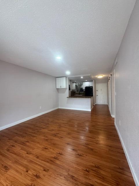 6080 Forest Hill Blvd Unit 201, West Palm Beach, FL 33415 - unfurnished living room featuring wood finished floors, a textured ceiling, and baseboards