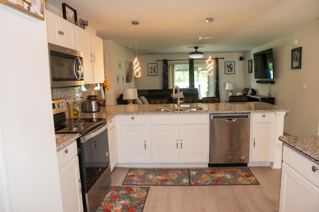 1122 SW California Blvd SW, Port Saint Lucie, FL 34953 - kitchen featuring appliances with stainless steel finishes, a sink, open floor plan, light wood-type flooring, and white cabinets