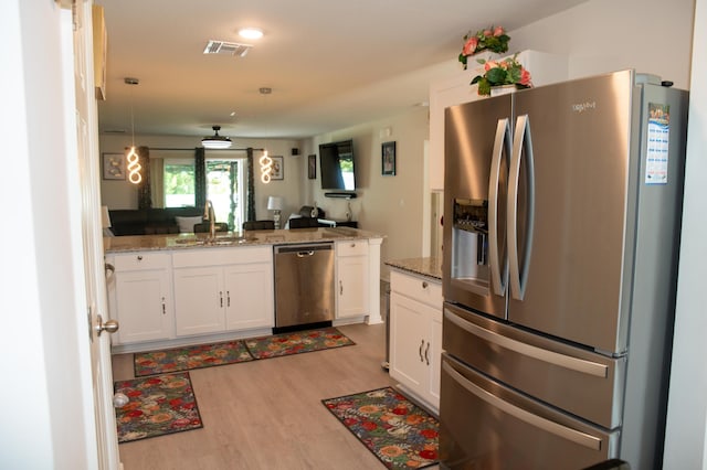 1122 SW California Blvd SW, Port Saint Lucie, FL 34953 - kitchen with appliances with stainless steel finishes, a sink, a peninsula, light wood finished floors, and white cabinetry