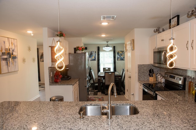 1122 SW California Blvd SW, Port Saint Lucie, FL 34953 - kitchen featuring appliances with stainless steel finishes, a sink, light stone counters, and white cabinetry