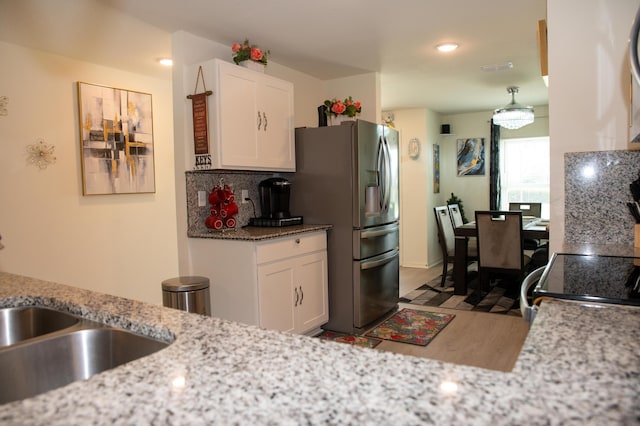 1122 SW California Blvd SW, Port Saint Lucie, FL 34953 - kitchen featuring stainless steel refrigerator with ice dispenser, wood finished floors, white cabinetry, a sink, and recessed lighting