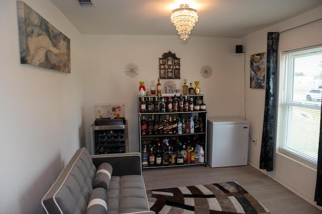 1122 SW California Blvd SW, Port Saint Lucie, FL 34953 - bar area featuring refrigerator, beverage cooler, a chandelier, and wood finished floors