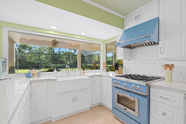 4633 Holly Dr, Palm Beach Gardens, FL 33418 - kitchen featuring high end stainless steel range oven, exhaust hood, a sink, decorative backsplash, and white cabinetry