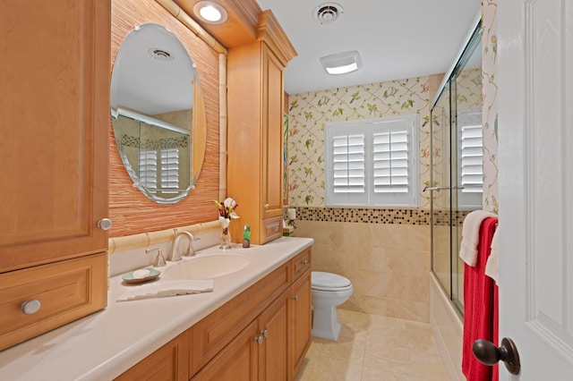 4633 Holly Dr, Palm Beach Gardens, FL 33418 - bathroom with wallpapered walls, vanity, toilet, tile walls, and tile patterned floors