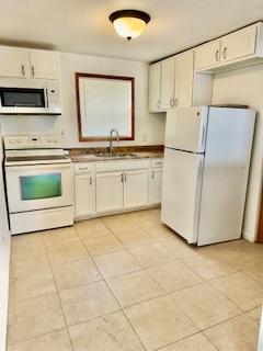 1260 Dr Martin Luther King Jr Blvd, Riviera Beach, FL 33404 - kitchen featuring white appliances, a sink, light tile patterned floors, and white cabinets