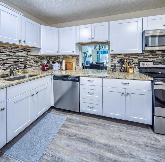 1516 S Lakeside Dr Unit 205, Lake Worth Beach, FL 33460 - kitchen featuring appliances with stainless steel finishes, backsplash, light wood-style floors, light stone counters, and white cabinets