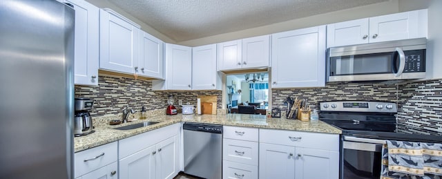 1516 S Lakeside Dr Unit 205, Lake Worth Beach, FL 33460 - kitchen with appliances with stainless steel finishes, a textured ceiling, decorative backsplash, white cabinets, and light stone countertops