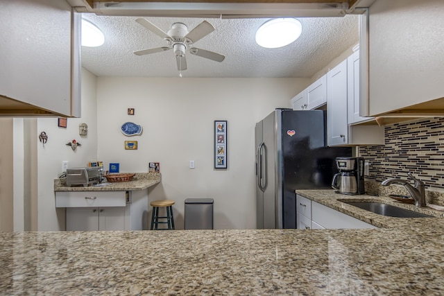 1516 S Lakeside Dr Unit 205, Lake Worth Beach, FL 33460 - kitchen featuring decorative backsplash, white cabinetry, light stone counters, a ceiling fan, and stainless steel fridge