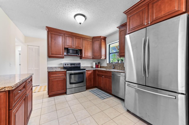 17183 76th St N, Loxahatchee, FL 33470 - kitchen featuring stainless steel appliances, a sink, light stone countertops, light tile patterned floors, and a textured ceiling