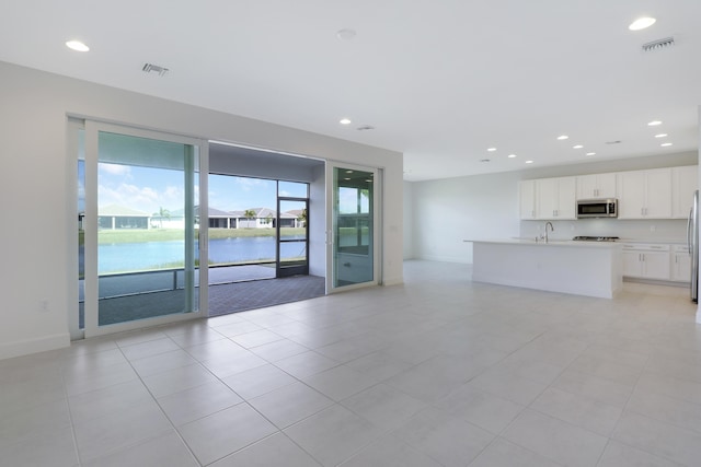 13439 SW River Rock Rd, Port Saint Lucie, FL 34987 - unfurnished living room featuring recessed lighting, light tile patterned floors, baseboards, a sink, and a water view