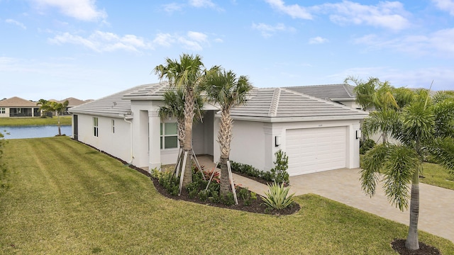 13439 SW River Rock Rd, Port Saint Lucie, FL 34987 - view of front of home featuring an attached garage, a water view, stucco siding, and a front lawn