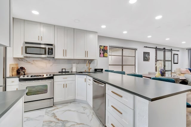 21695 Tall Palm Cir Unit 4B, Boca Raton, FL 33433 - kitchen featuring appliances with stainless steel finishes, a peninsula, a sink, a barn door, and recessed lighting