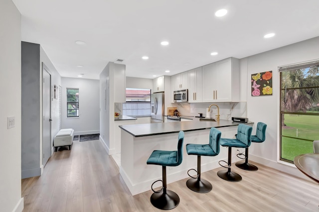 21695 Tall Palm Cir Unit 4B, Boca Raton, FL 33433 - kitchen with stainless steel appliances, baseboards, a kitchen bar, light wood-type flooring, and recessed lighting