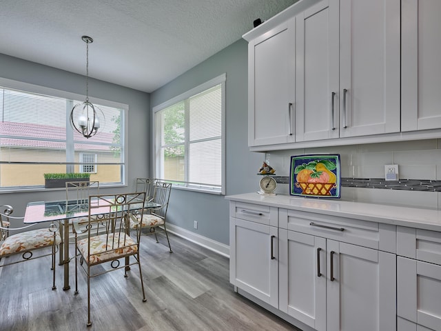 8194 Via Bolzano, Lake Worth, FL 33467 - dining area with light wood-style flooring, a chandelier, baseboards, and a textured ceiling