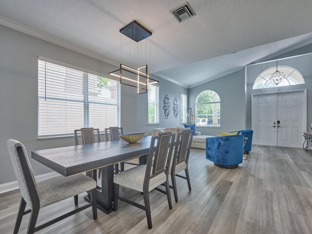 8194 Via Bolzano, Lake Worth, FL 33467 - dining space featuring a chandelier, wood finished floors, ornamental molding, vaulted ceiling, and a textured ceiling