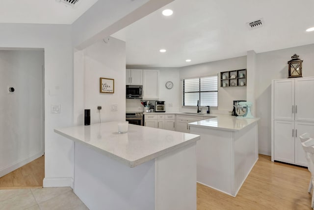 146 Weybridge Cir Unit B, Royal Palm Beach, FL 33411 - kitchen with appliances with stainless steel finishes, a peninsula, a sink, white cabinets, and light countertops