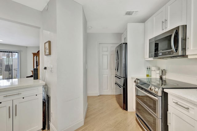 146 Weybridge Cir Unit B, Royal Palm Beach, FL 33411 - kitchen featuring stainless steel appliances, light countertops, light wood-style flooring, white cabinetry, and baseboards