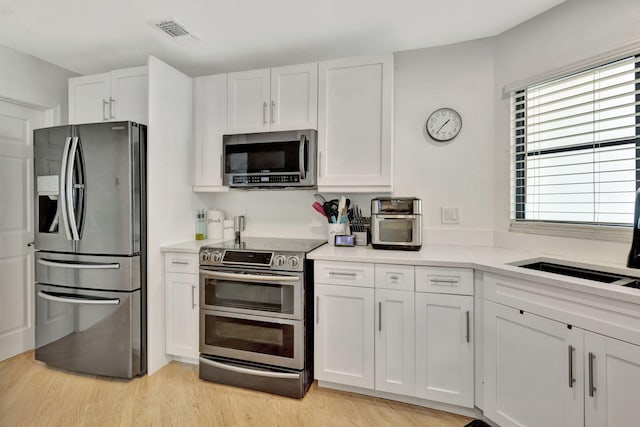 146 Weybridge Cir Unit B, Royal Palm Beach, FL 33411 - kitchen with stainless steel appliances, white cabinets, light wood finished floors, and light countertops