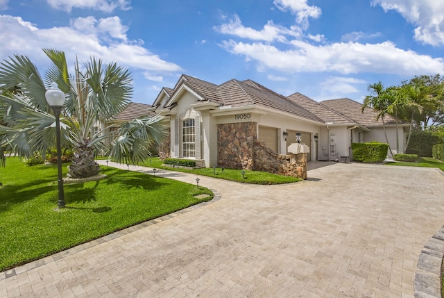 19050 SE Kokomo Ln, Jupiter, FL 33458 - view of front of property with a garage, decorative driveway, a front lawn, stucco siding, and stone siding