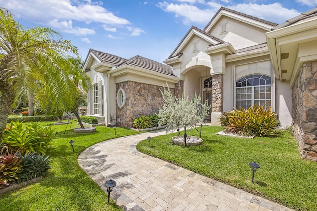 19050 SE Kokomo Ln, Jupiter, FL 33458 - view of front of property featuring stone siding, a front yard, stucco siding, and a tile roof