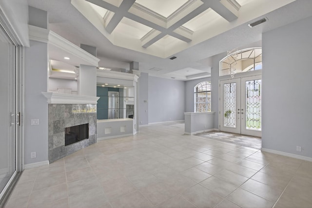 19050 SE Kokomo Ln, Jupiter, FL 33458 - unfurnished living room with french doors, coffered ceiling, tile patterned floors, a high ceiling, and a tiled fireplace