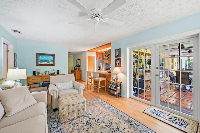 9494 SE Cove Point St, Jupiter, FL 33469 - living area featuring wood finished floors, a ceiling fan, a textured ceiling, and french doors