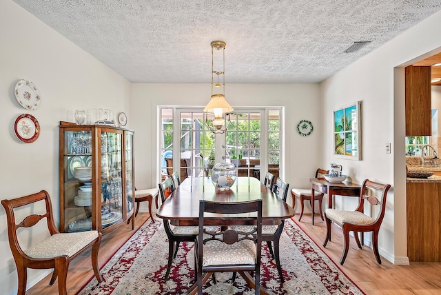 9494 SE Cove Point St, Jupiter, FL 33469 - dining room featuring light wood finished floors, a textured ceiling, and french doors