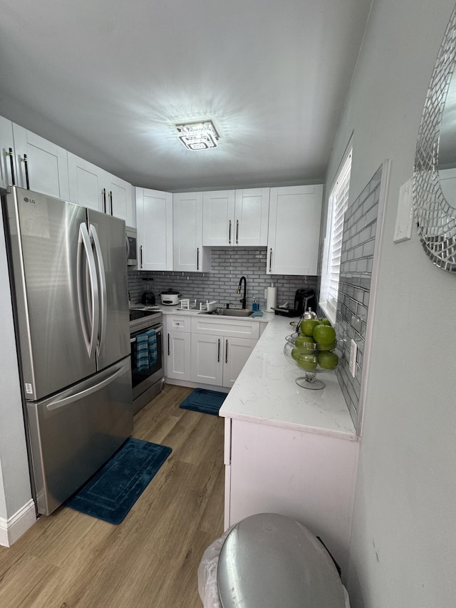 203 S Windsor I Unit 203, West Palm Beach, FL 33417 - kitchen featuring stainless steel appliances, a sink, light wood-type flooring, white cabinetry, and tasteful backsplash