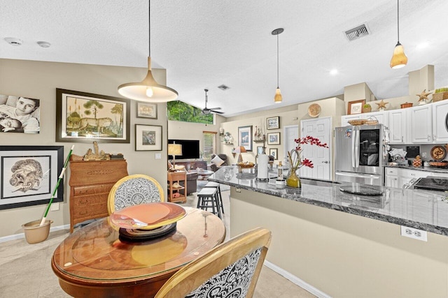 16243 E Calder Dr, Loxahatchee, FL 33470 - kitchen with smart refrigerator, decorative light fixtures, white cabinetry, dark stone countertops, and vaulted ceiling