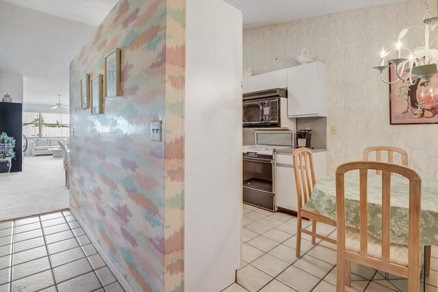 7610 Tahiti Ln Unit 201, Lake Worth, FL 33467 - kitchen with white range oven, wallpapered walls, black microwave, white cabinets, and light tile patterned flooring